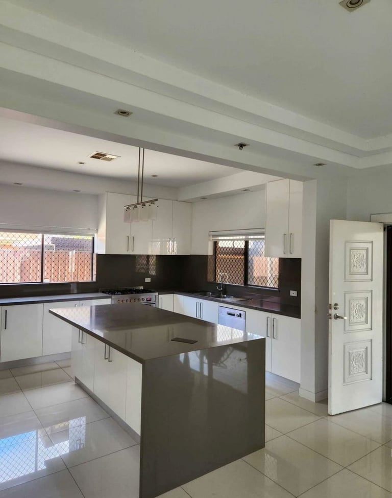 Modern kitchen with white cabinetry, dark countertop island, black backsplash, and patterned window shades