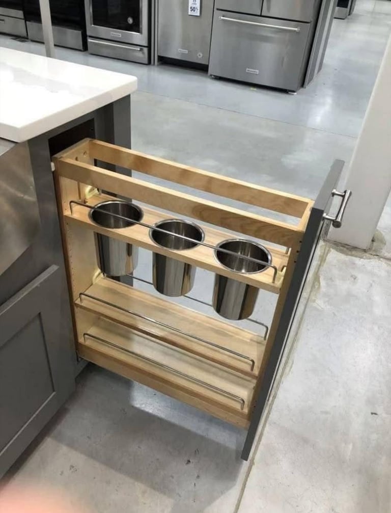 Open kitchen cabinet drawer with wooden organizer holding three stainless steel pots and lower storage compartments