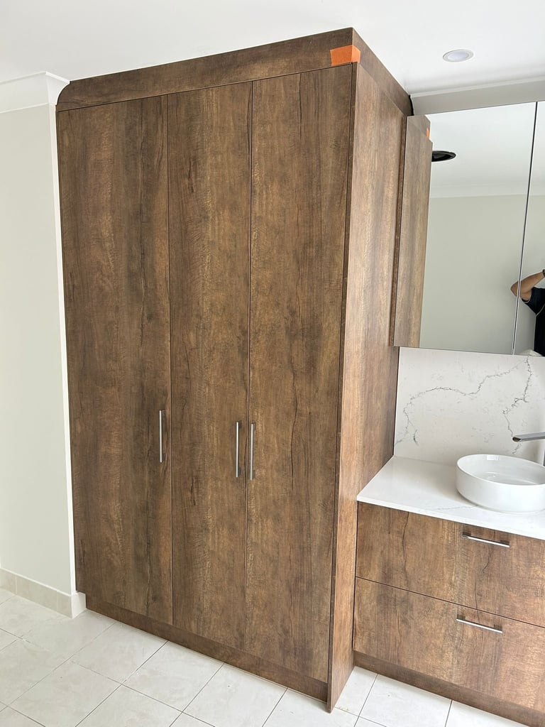 Large wooden wardrobe with double doors in a modern bathroom next to white marble vanity