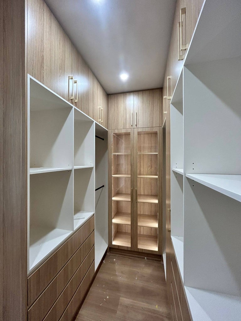 Modern walk-in closet with built-in white shelving units, wooden cabinetry, and recessed ceiling lights