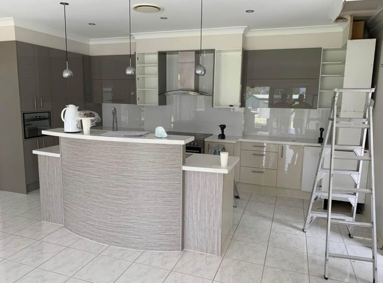 Modern kitchen with gray and white cabinetry, curved island, stainless steel appliances, and pendant lighting