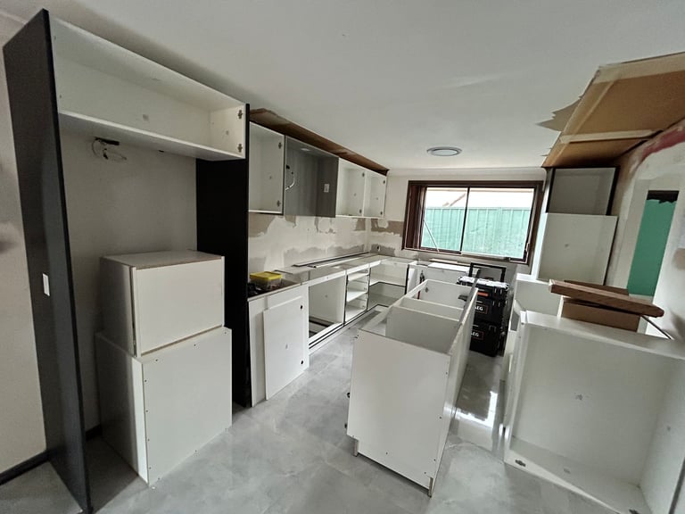 Empty kitchen showroom or warehouse with white appliances and cabinets arranged for display