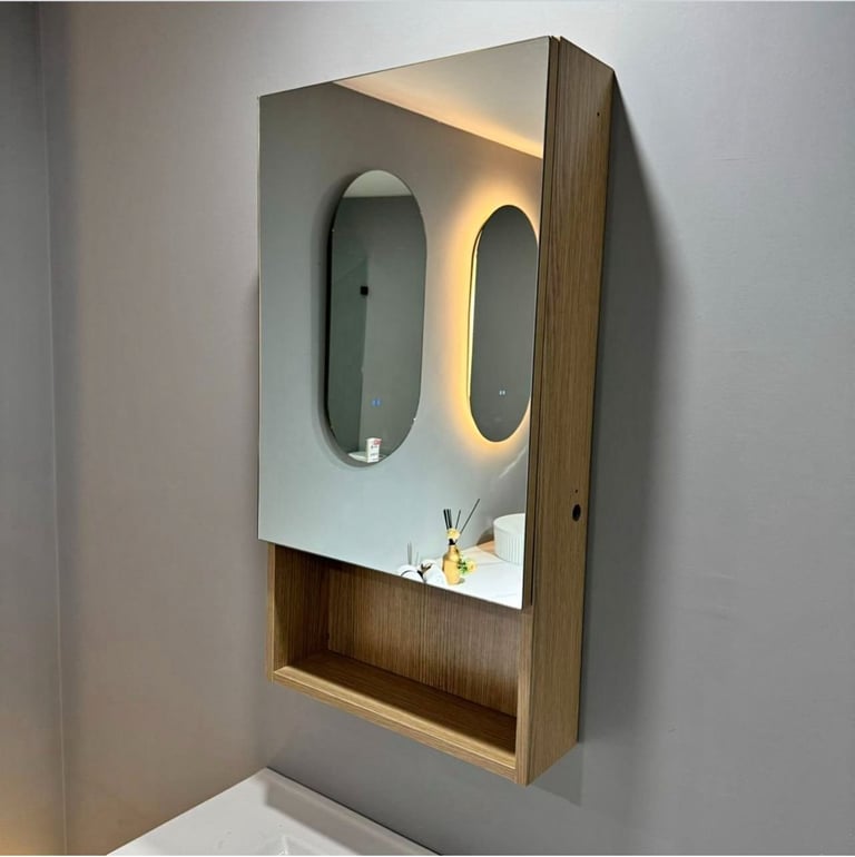 Modern wall-mounted medicine cabinet with dual oval mirrors, LED backlighting, and wooden frame with open shelf storage