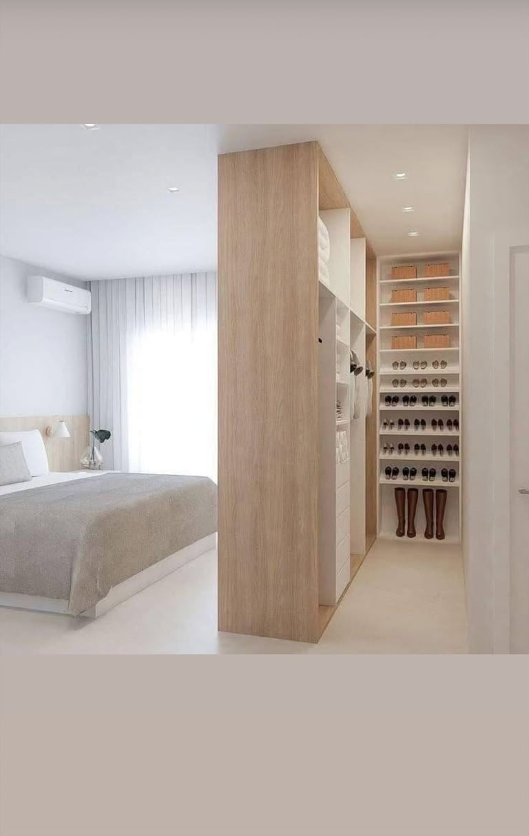 Modern bedroom with wooden partition wall separating sleeping area from walk-in closet with organized shelving and shoe storage