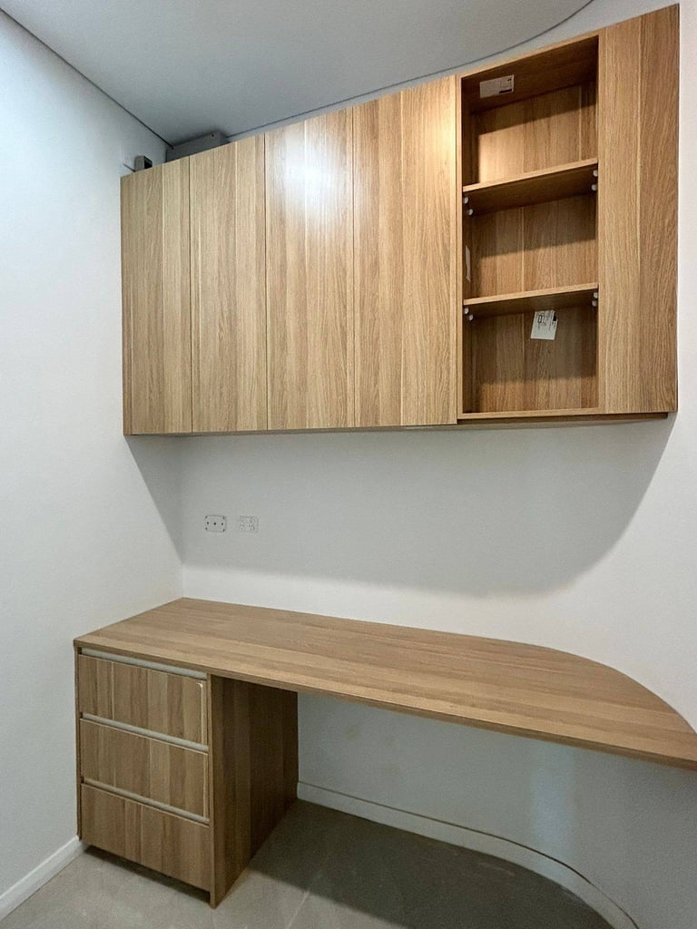 Modern wooden built-in desk and storage cabinets with open shelving in a minimalist white room