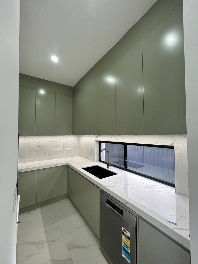 Modern kitchen with sage green cabinetry, white marble countertops, stainless steel appliances, and recessed ceiling lights